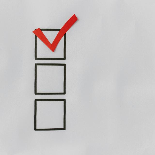 A simple graphic image of a checklist featuring three boxes aligned vertically. The top box has a red checkmark in it.
