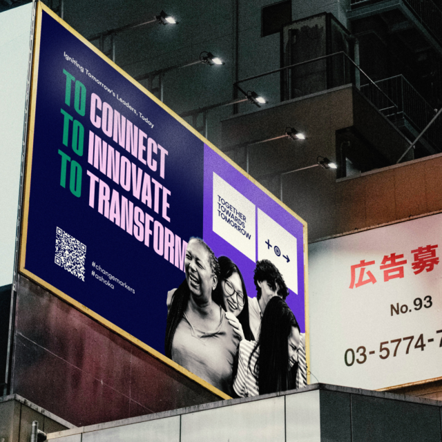 A photoshopped image of an advertisement for the Together Towards Tomorrow Changemaker Challenge superimposed onto a billboard featuring both the brand colors, a photo of group of people in black and white, and text..