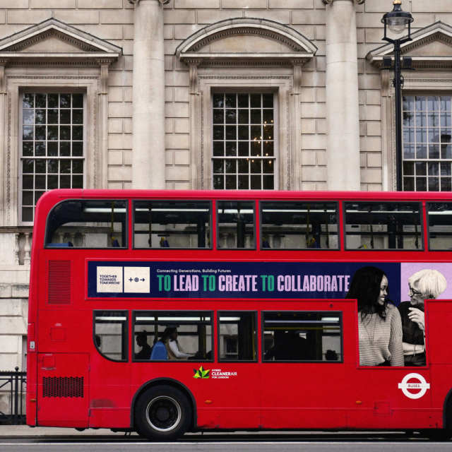 A photoshopped image of an advertisement for the Together Towards Tomorrow Changemaker Challenge superimposed onto a bus featuring both the brand colors, a photo of group of people in black and white, and text..
