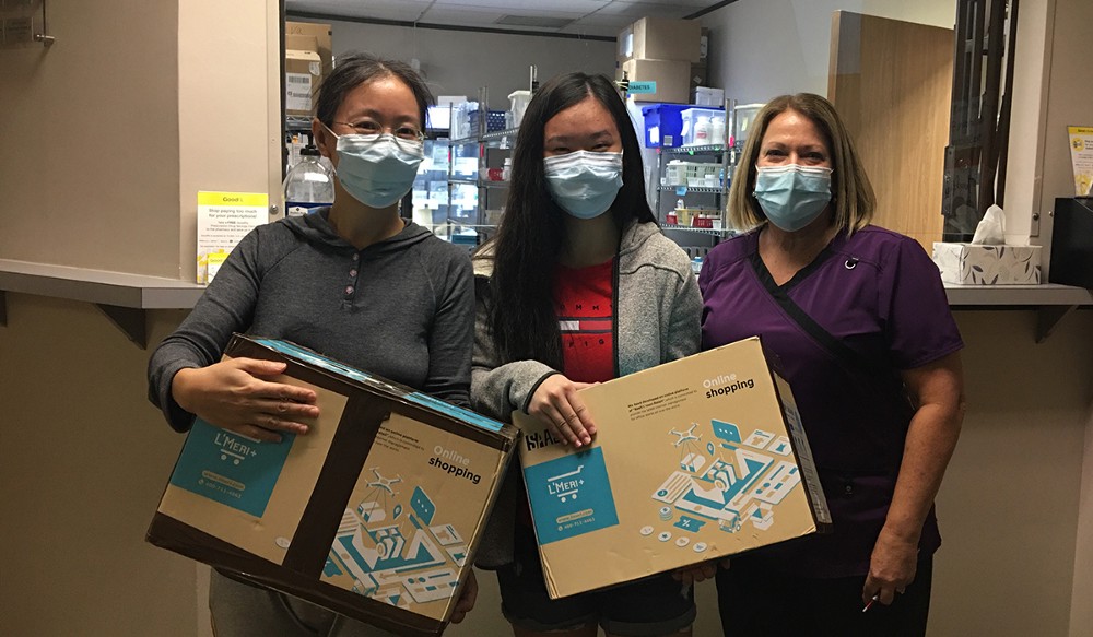 Two women holding each one a box next to a woman dressed as a nurse.