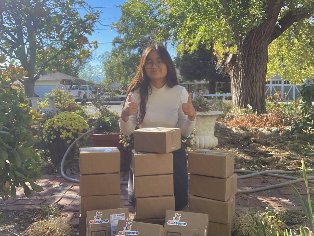 Anne standing with AUesome therapy kits in small cardboard boxes