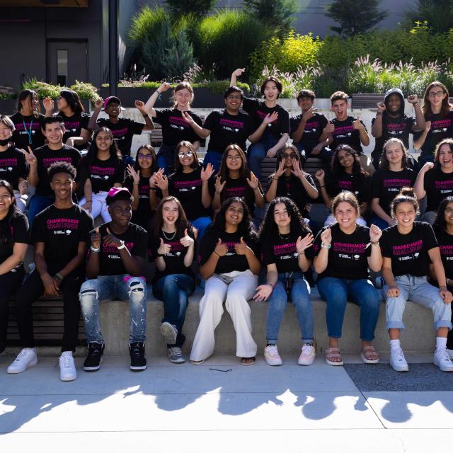 A diverse group of young people, ages 13 to 18 chosen as finalists for the T-Mobile 2022 Changemaker Challenge, sitting on oversized steps posing for a photo.