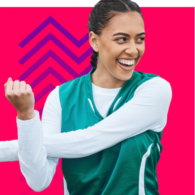 A photo of a young woman with tan skin and brown hair wearing a green jersey over a white shirt. She is stretching her arms across her chest, smiling and looking to something out of frame. She is superimposed over a magenta background and a purple chevron graphic.