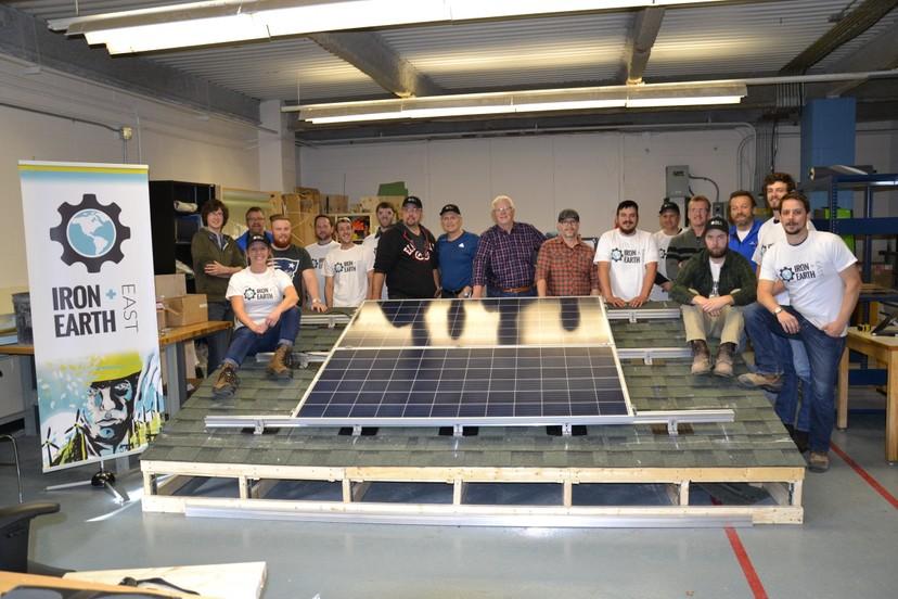Changemakers from Iron and Earth gathering around a solar panel. 