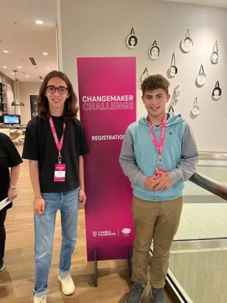Santiago Lupi (left) and Jed Greenwald (right) at 2022 T-Mobile Changemaker Challenge. They are standing in front of a pink banner that says "Changemaker Challenge."
