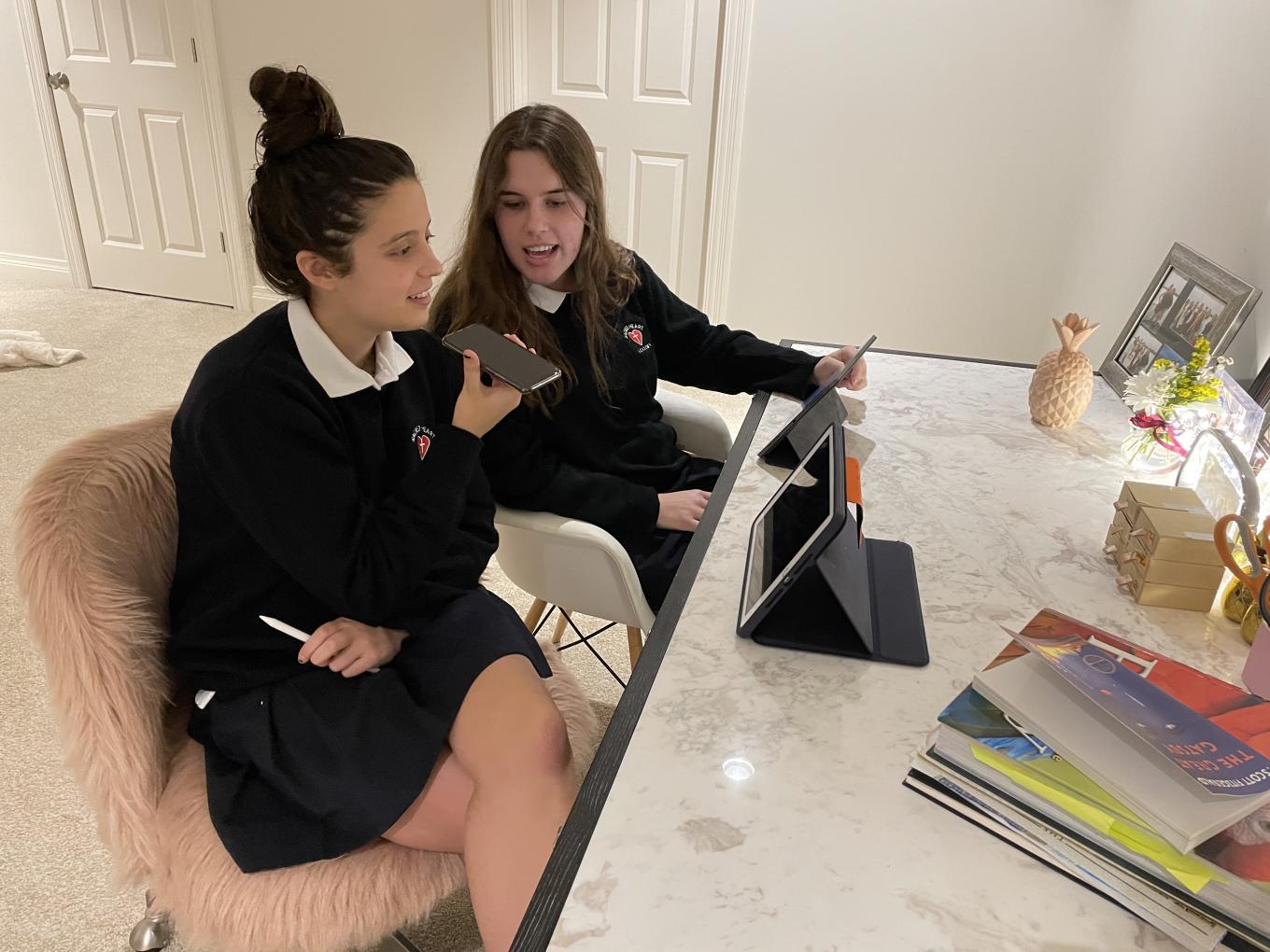 Jacqueline and Amelie sitting at a white desk working on their project.