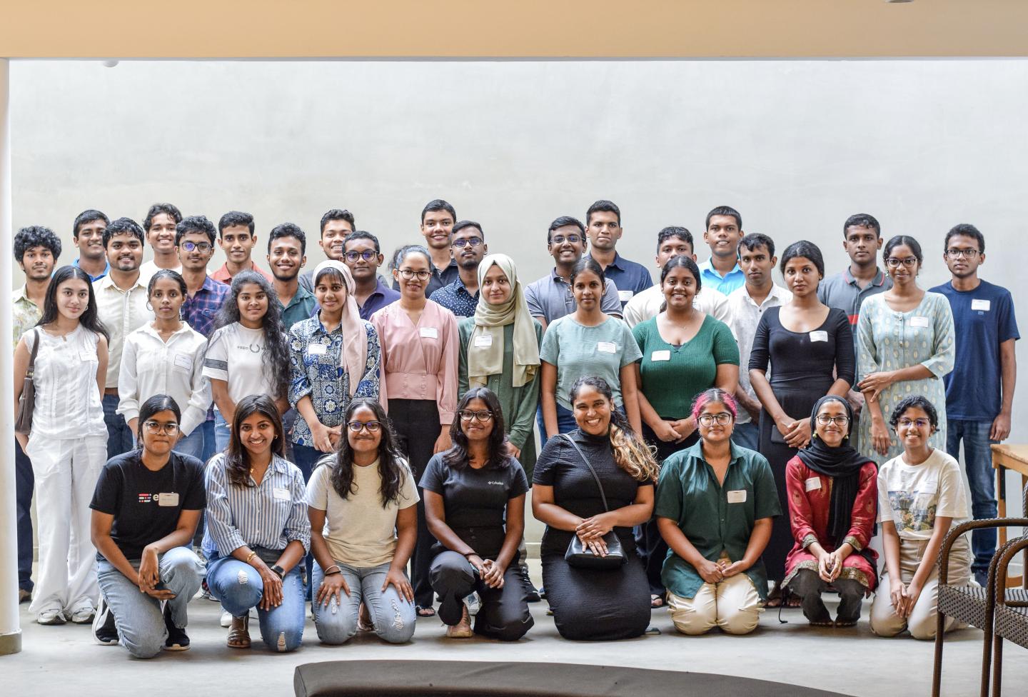 A large group of people posing in front of a white wall.