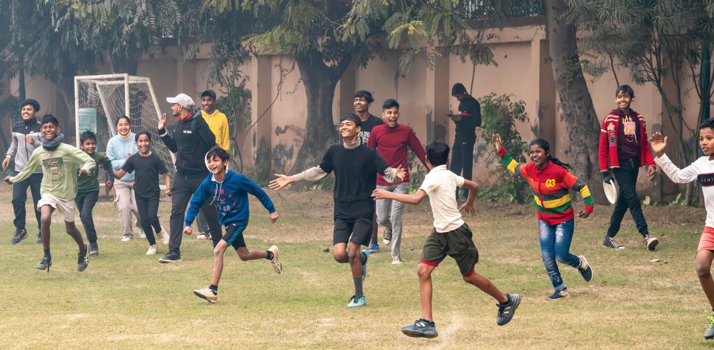 A group of young people running across a field as they play ultimate frisbee