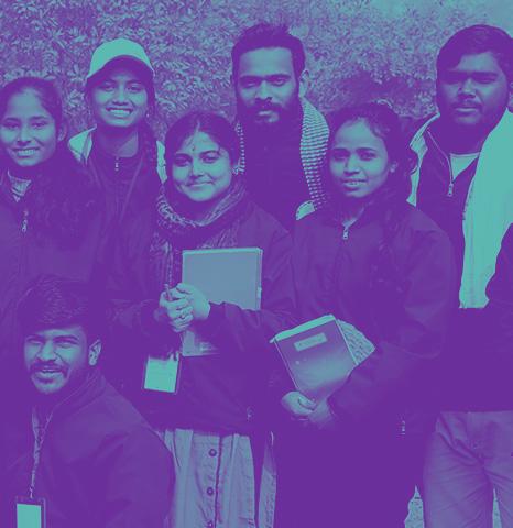 A stylized photo of seven Indian young people wearing casual clothing and posing in a line for the photo. Several are holding notebooks. The photo has been posterized in purple and teal, the Ambition Accelerator brand colors.