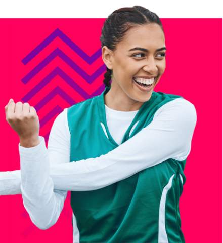 A photo of a young woman with tan skin and brown hair wearing a green jersey over a white shirt. She is stretching her arms across her chest, smiling and looking to something out of frame. She is superimposed over a magenta background and a purple chevron graphic.